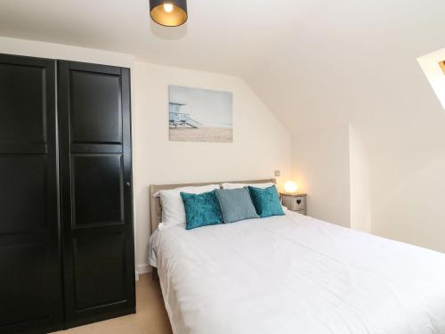 sypialnia z białym łóżkiem z niebieskimi poduszkami w obiekcie Harbour Reach 6 w mieście Weymouth