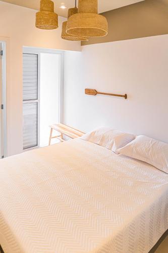 a bedroom with a white bed and a window at Cobertura Premium Hidro 3Quartos 2Vagas Ubatuba in Ubatuba