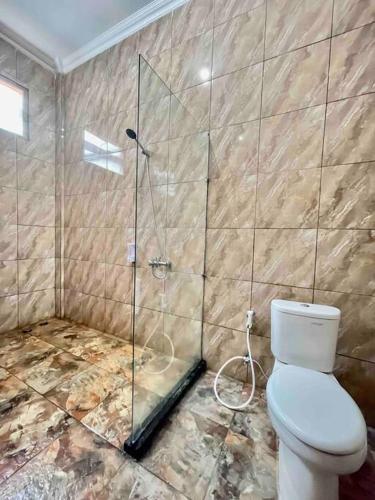 a bathroom with a toilet and a glass shower at Dhanis House Bogor in Cibanawak