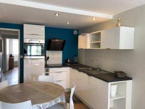 - une cuisine avec des placards blancs et une table avec un évier dans l'établissement Mayfair, à Le Touquet-Paris-Plage