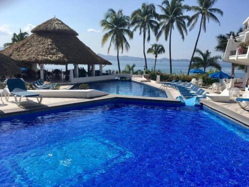einen Pool im Resort mit Stühlen und Palmen in der Unterkunft Hermoso condominio en Bahía Manzanillo in Manzanillo