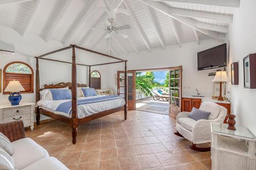 a bedroom with a canopy bed and a tv in it at Villa Mer Soleil in Marigot