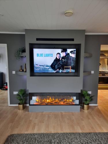 a living room with a tv and a fireplace at Windrush Turret Lodge in South Cerney