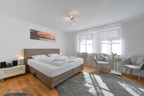 - une chambre blanche avec un lit et deux chaises dans l'établissement Ferienwohnung Ferienparadies, à Füssen