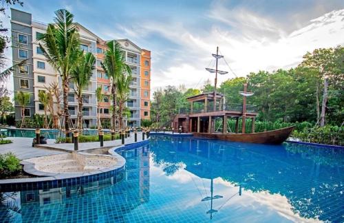 a large swimming pool with a boat in front of a building at TITLE NaiYang apartment-300m from sea in Phuket Town