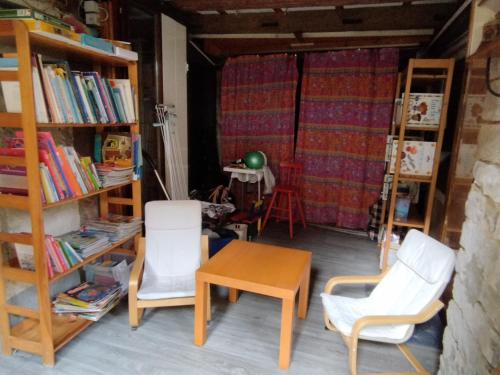 a room with two chairs and a table and bookshelves at Le havre de grès in Lohr