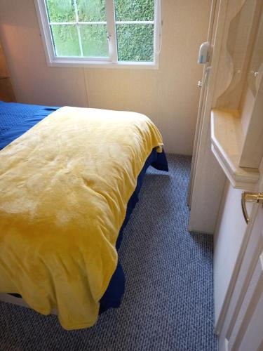 a yellow bed in a room with a window at Adorable Caravan in Western Lakes in Workington