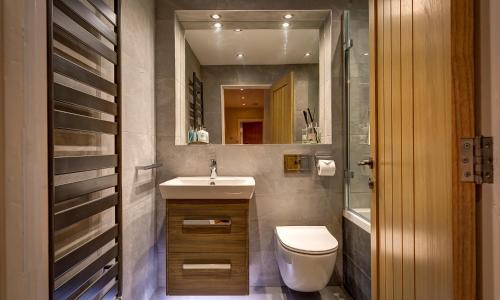 a bathroom with a sink and a toilet and a mirror at Hart Head Barn in Ambleside