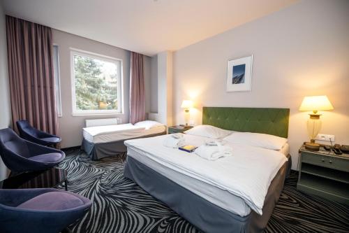 a hotel room with two beds and a window at Parkhotel Carlsbad Inn in Karlovy Vary