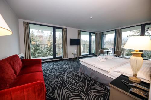 カルロヴィ・ヴァリにあるParkhotel Carlsbad Innのベッドと赤いソファが備わるホテルルームです。