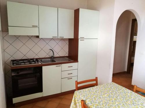 eine Küche mit weißen Schränken, einer Spüle und einem Tisch in der Unterkunft Appartamento Liam in Marzamemi
