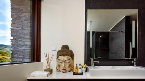 een badkamer met een wastafel en een grote spiegel bij Quinta de Merouço - Villa do Rolapipas in Alijó