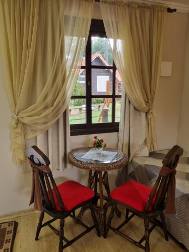 a table and two chairs in a room with a window at Pousada Caliandra Da Serra in Canela
