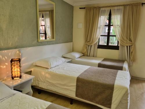 a hotel room with two beds and a lamp at Pousada Caliandra Da Serra in Canela
