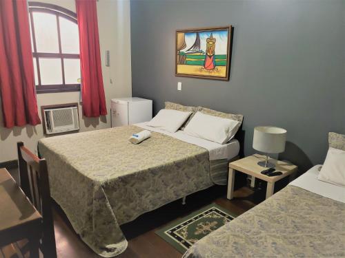 una camera d'albergo con due letti e un tavolo con sedie di Pousada Anexo a Niterói