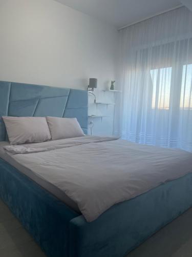 a bedroom with a blue bed and a window at Panorama 901 in Oradea