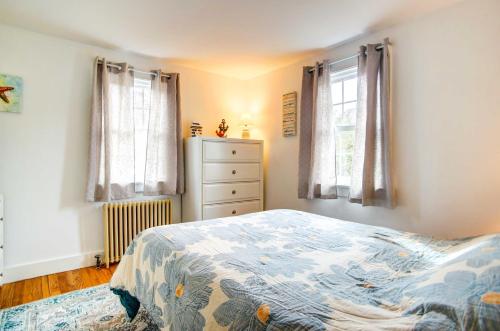 a bedroom with a bed and a dresser and two windows at 2 Mi to Beach Coastal Retreat in Hyannis! in Hyannis