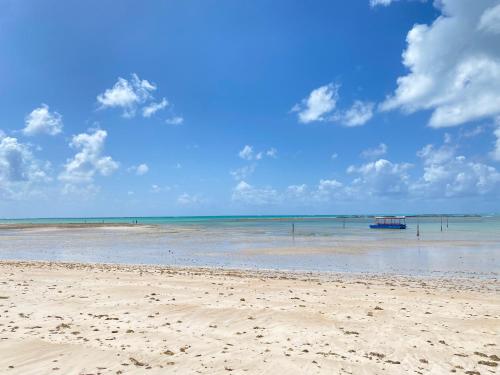 a beach with a boat in the water at Casa de Dora in São Miguel dos Milagres