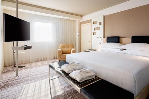 a bedroom with a large white bed and a flat screen tv at Madrid Marriott Auditorium Hotel & Conference Center in Madrid