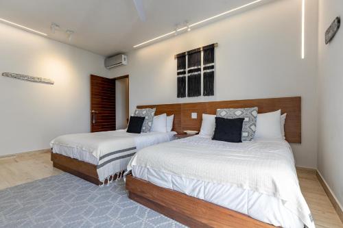 two beds in a room with white walls at 308-303 Beautiful apartments with 3 bedrooms in Tulum