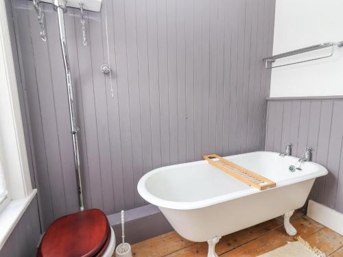 een wit bad in een badkamer met een rode stoel bij The Merchant's House in Kilrush