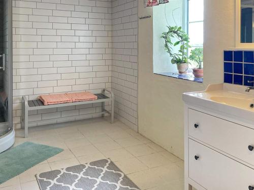 ein Badezimmer mit einem Waschbecken und einer Dusche mit einer Bank in der Unterkunft Holiday home SJÖBO in Vollsjö
