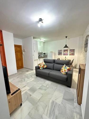 sala de estar con sofá y cocina en Moderno apartamento junto al mar- Apartamentos Don Diego, en Torremolinos
