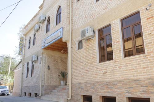 a large brick building with stairs in front of it at Sultanat Hotel in Samarkand