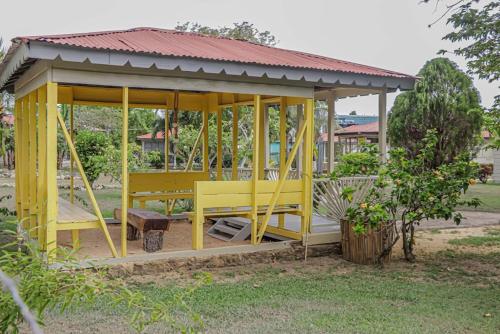 a yellow gazebo with a bench in a yard at Little Bay Hideaway in Little Bay
