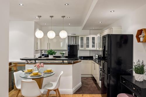 eine Küche mit einem Tisch und einem schwarzen Kühlschrank in der Unterkunft Park Street Mayfair apartments in London