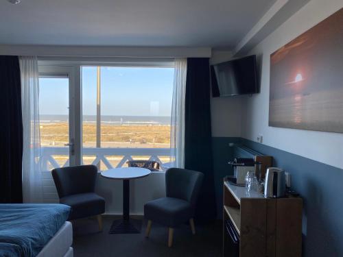 a hotel room with a bed and a table and chairs at Bed&Breakfast aan Strand in Katwijk aan Zee