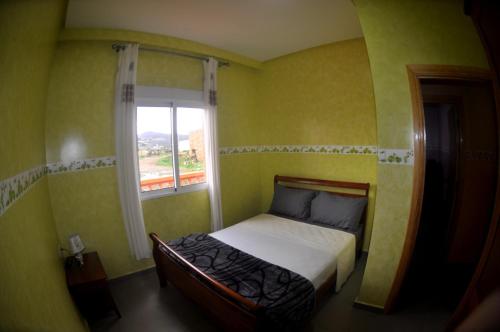 een kleine slaapkamer met een bed en een raam bij Jbel Moussa Lodge in Rcham