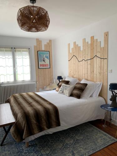 Schlafzimmer mit einem großen Bett mit einem Kopfteil aus Holz in der Unterkunft La Bigourdane in Gerde