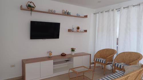 a living room with a flat screen tv and chairs at Chicama D'Amore - Family Place & Wave Paradise - Parking & kidszone - on Puerto Chicama in Puerto Chicama