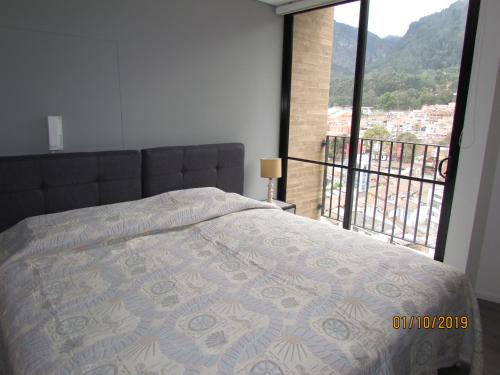 a bedroom with a bed and a large window at Enjoy In Bogotá in Bogotá