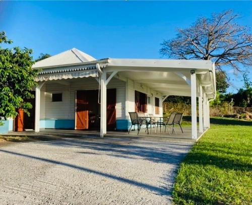una pérgola blanca en una casa con una mesa en Villa Créole vue sur mer des Caraïbes, en Le Carbet