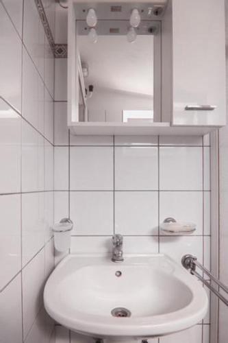 a white bathroom with a sink and a mirror at Apartman Ponte Martini in Punat