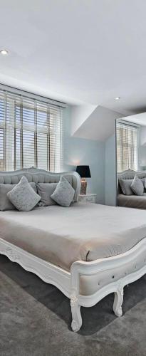 a bedroom with a large white bed with pillows at Hampstead Opulence Apartment - Luxurious Split Level Property in London