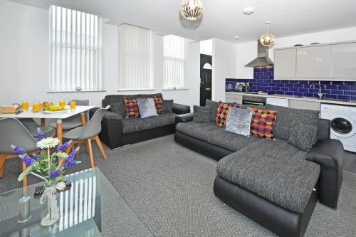 ein Wohnzimmer mit Sofas und einem Tisch sowie eine Küche in der Unterkunft Smithfield Apartments - Gated Executive City Centre Apartments in Stoke on Trent