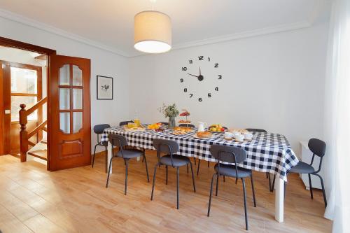 a dining room table with chairs and a clock on the wall at 158A Triplex Rinconin con piscina in Gijón