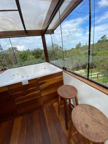 a bathroom with a tub and two stools in front of a window at CASA DA MATA - LAVRAS NOVAS in Lavras Novas