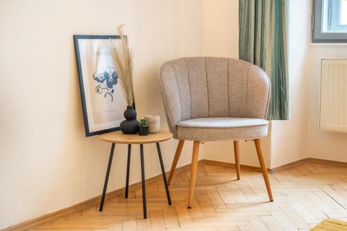a chair and a side table in a room at Primavera - Castle view apartments in Prague