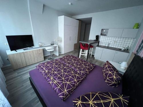 1 Schlafzimmer mit einem lila Bett und einer Küche in der Unterkunft MIDTOWN Apartments in Stuttgart