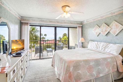 a bedroom with a bed and a television and a balcony at Land's End 1-307 Gulf View in St. Pete Beach