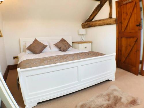 a bedroom with a white bed with a wooden door at 2 Bed Classy Peak District Cottage Barn Near Alton Towers, Polar Bears, Chatsworth House in Whiston
