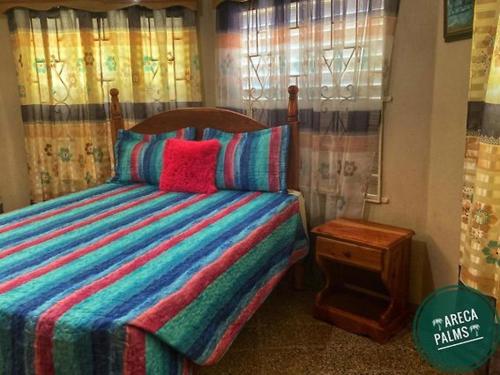 a bedroom with a bed with a colorful striped comforter at Areca Palms in Port Antonio