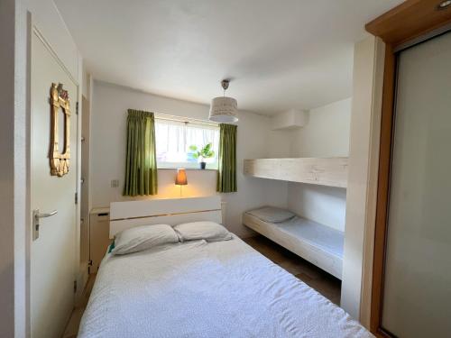 a small bedroom with a bed and a window at Gelijkvloers Vakantieappartement 150m van Strand Egmond aan Zee in Egmond aan Zee