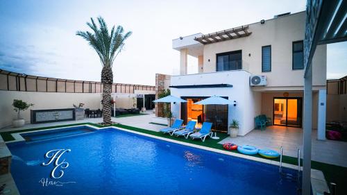 a swimming pool in front of a house with a palm tree at Hero's Chalet - Deadsea in Al Rama