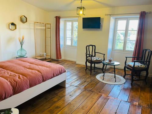 a bedroom with a bed and two chairs and a table at Les Dames Jeannes in Jarnac