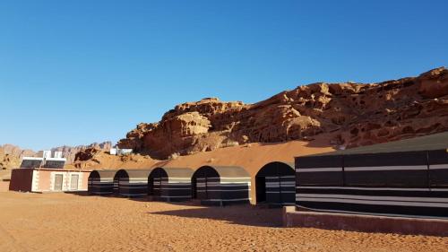 a building in the desert with a mountain in the background at Golden Sands Camp in Wadi Rum